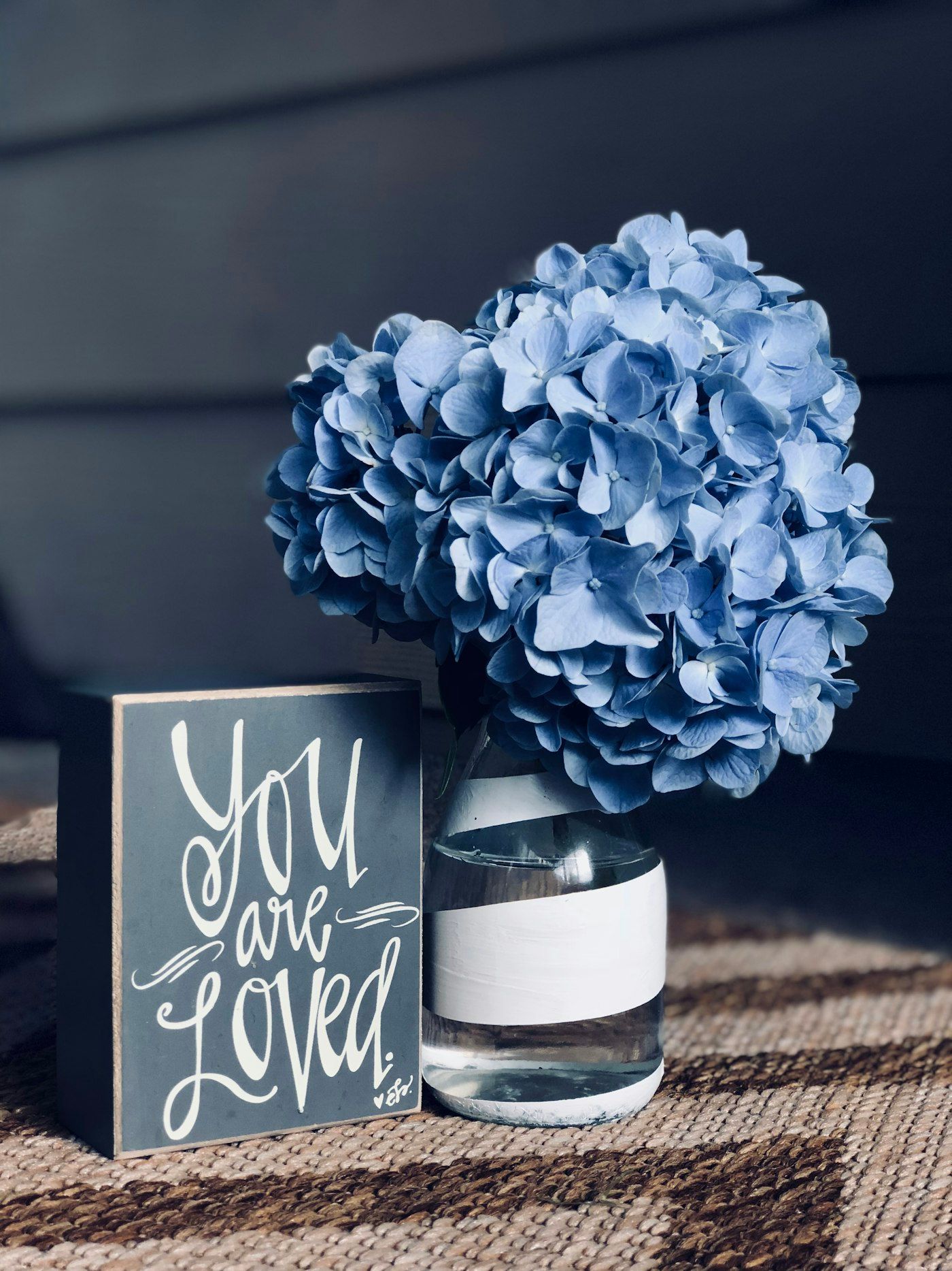 Cẩm tú cầu xanh trong lọ thủy tinh bên bảng chữ You are Loved